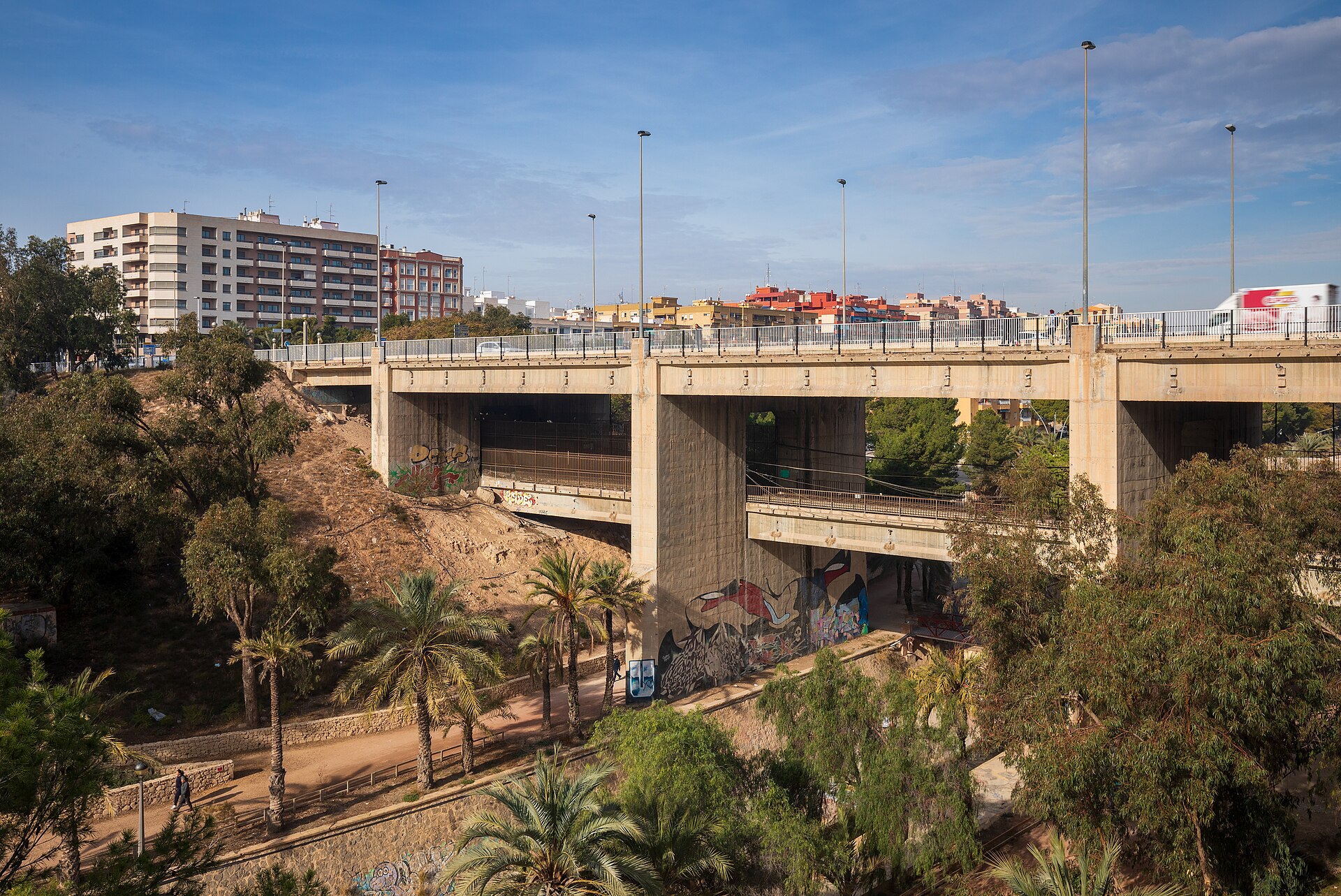 Puente del Ferrocarril crosses Riu Vinalopo in Elche, Alicante, Spain in 2024 January. View from Parc Municipal. On the upper level is the road and pedestrian access, whereas beneath goes the railway.